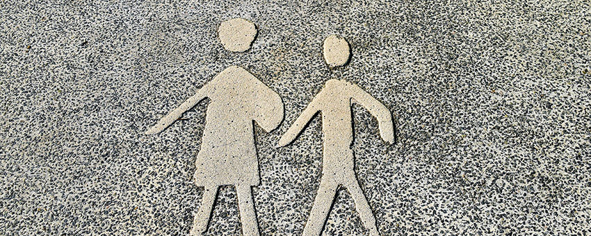 Fond gris moucheté. 2 personnages gravés, sous forme de pictogramme, marchent côte à côte