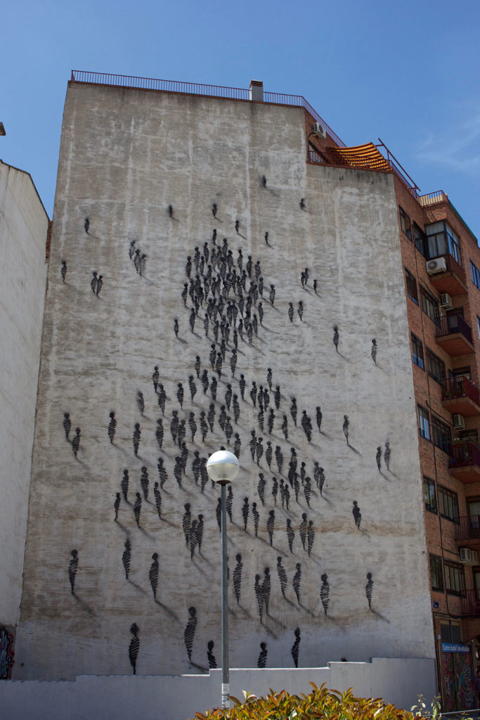 Oeuvre de street art. Mur parsemé de personnages de couleur noire.