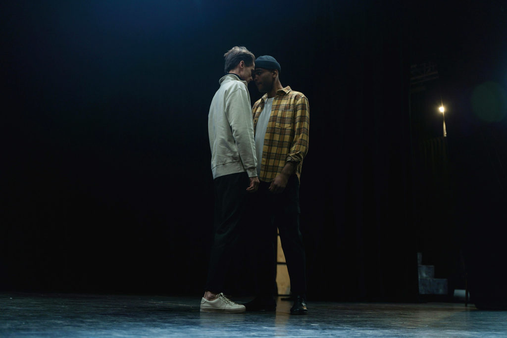 Scène de théâtre. Deux jeunes hommes tête contre tête.
