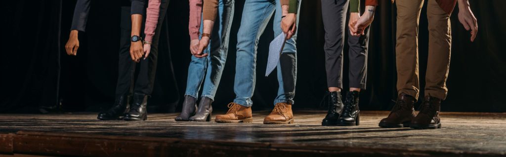 Personnes dont on ne voit que les jambes et les pieds sur une scène de théâtre