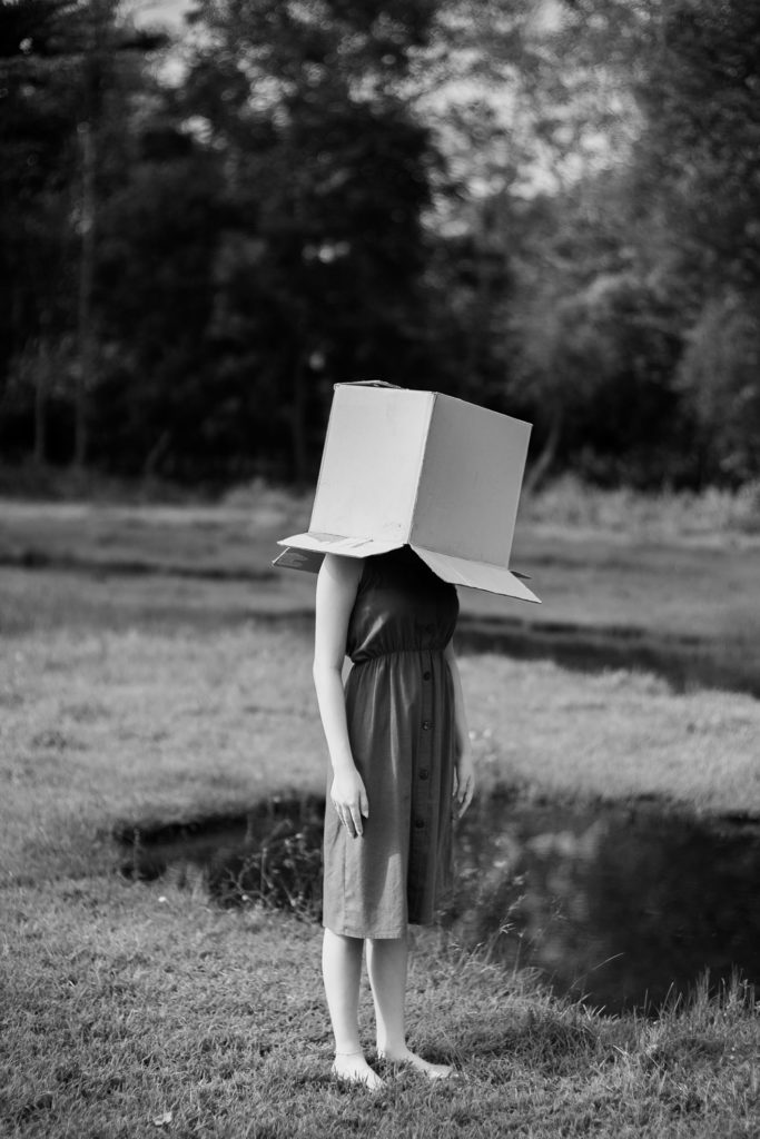 Femme debout dans la nature avec un carton sur la tête
