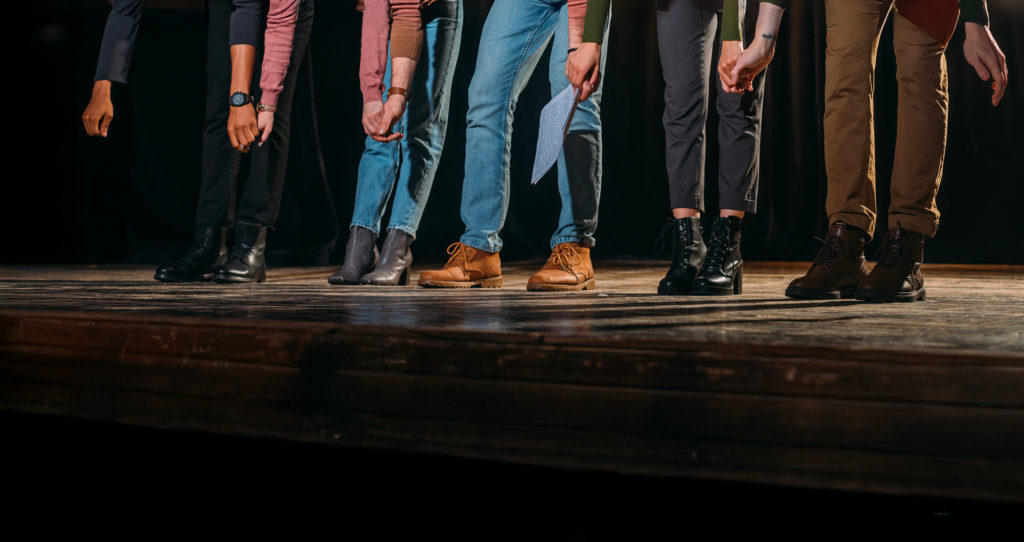 Personnes dont on ne voit que les jambes et les pieds sur une scène de théâtre