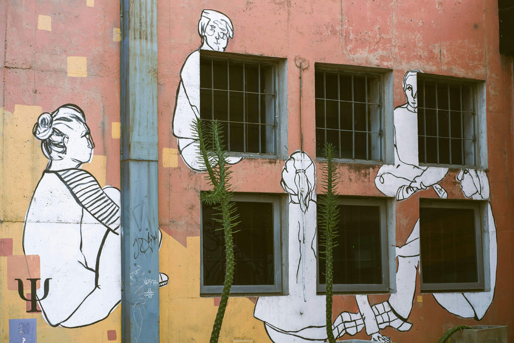 Un mur de couleur rose pale. Des personnages en blanc en train de discuter ont été dessinés sur le mur.