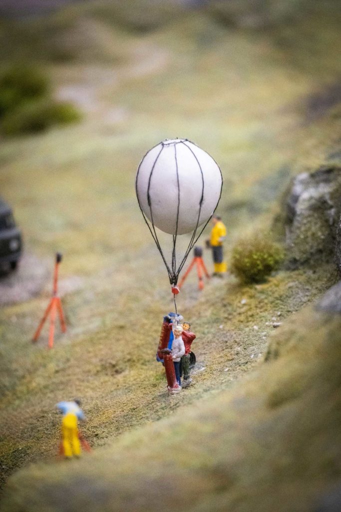 Petits personnages, l'un est attaché à une montgolfière
